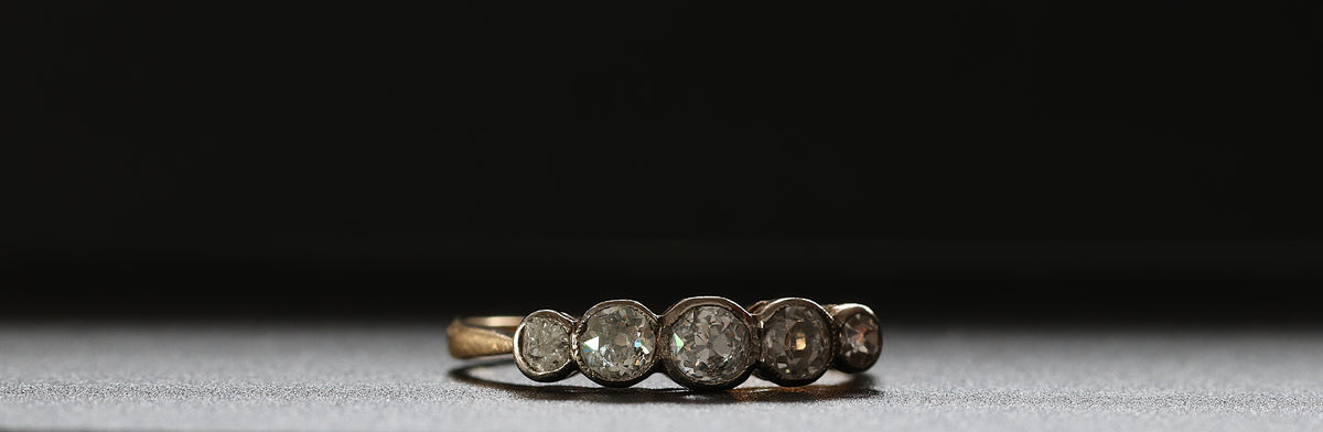 Five-stone old cut diamond ring in a dark setting